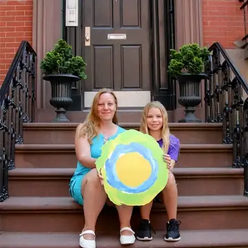 Two people sitting on a stoop with the Idealist logo between them.