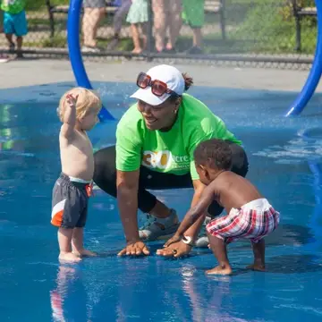 Educator playing with children in splash park