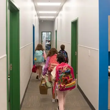 Students walk down the hall with their backpacks.