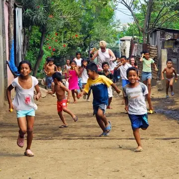 Nicaraguan children running through the street with a volunteer and kazoos in their hands.