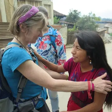 a western woman and a guatemalan women hug