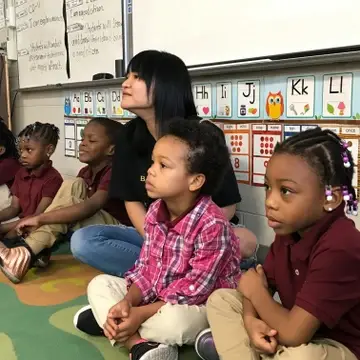 A teacher sitting with young students.