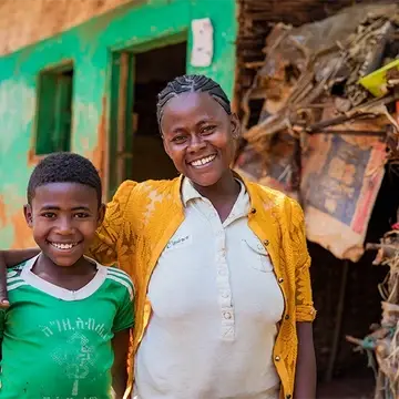 Luminos Second Chance student Mesfin and his mother outside their home in Ethiopia