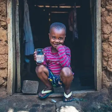 Young boy in Tanzania enjoys a glass of clean, safe water.