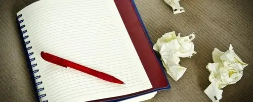 A notebook with balled up paper next to it.