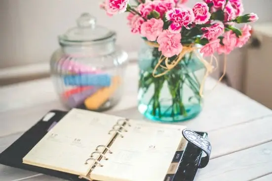 A planner and vase with flowers on a table.