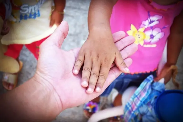 An adult's hand holds a child's hand.