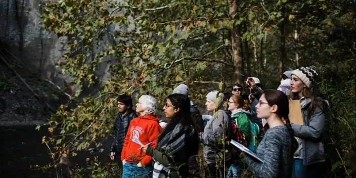Group of students and faculty exploring an outdoor space near a waterfall
