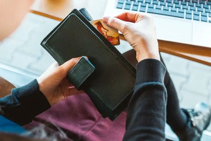 Manos sacando una tarjeta de crédito de una billetera