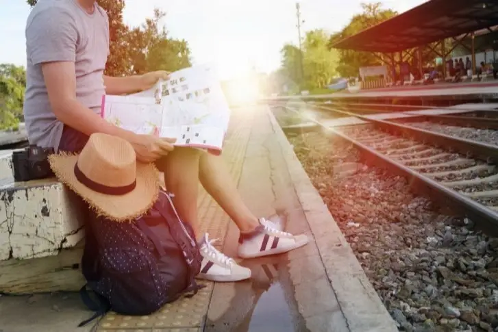 Una turista sentada mirando un mapa esperando al tren