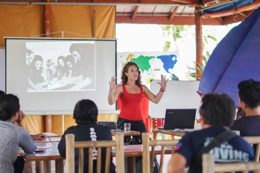 Luz gives a lecture to a group of students.