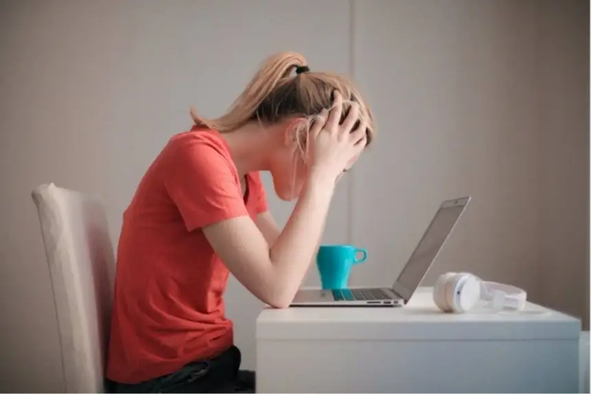 A woman looking frustrated at her laptop.