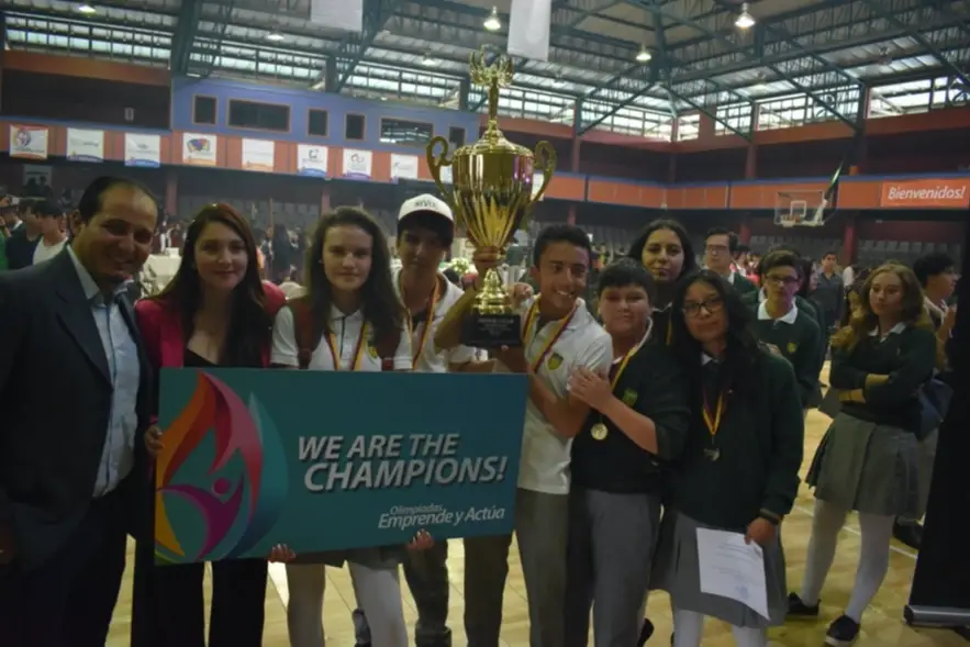 A group of young people wearing medals and holding up a trophy.