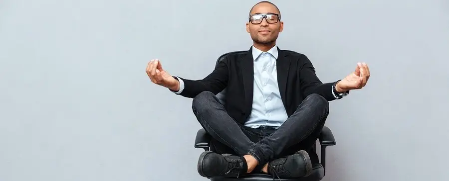 A man in a business suit meditates in a chair.