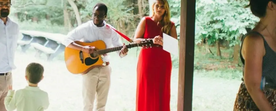 Charles Amuzie playing the acoustic guitar for an audience.