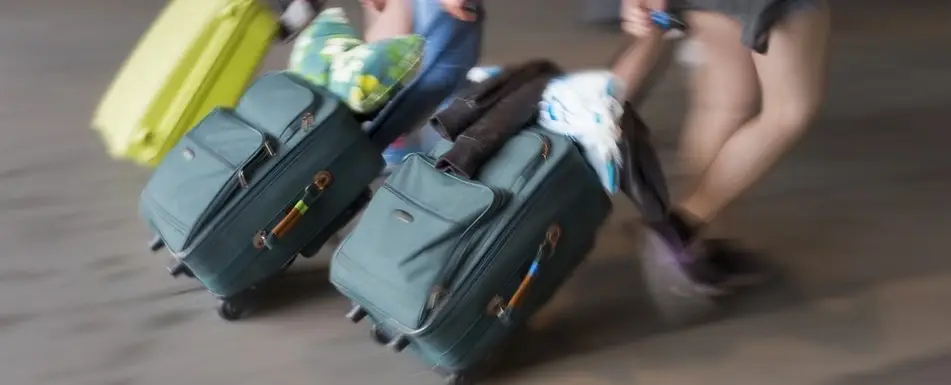 Two people walking with suitcases.