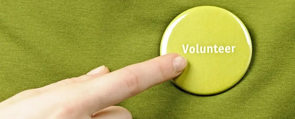 A person pointing to a button that says 'Volunteer'.