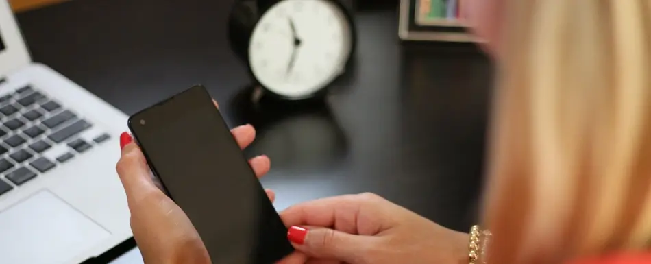 woman looking at phone with clock in background
