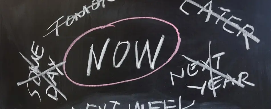 A chalkboard with words crossed out and 'Now' circled.