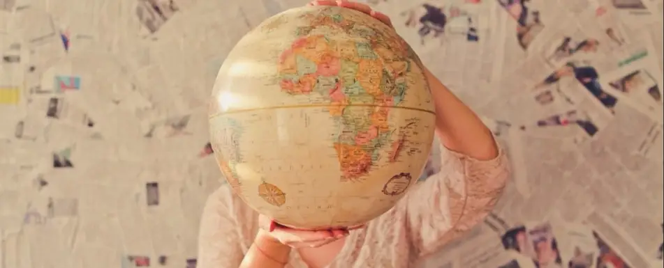 Someone holds a globe in front of their face.
