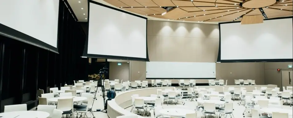 An empty conference room with chair and projector screens.