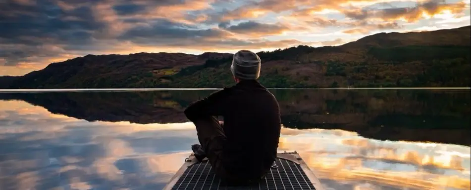 A man at a boardwalk looks out at a body of water.