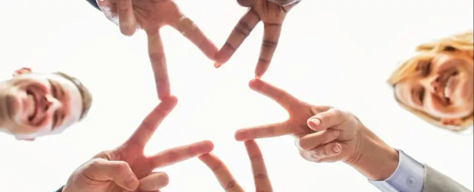 A group of people using their fingers to make a star.