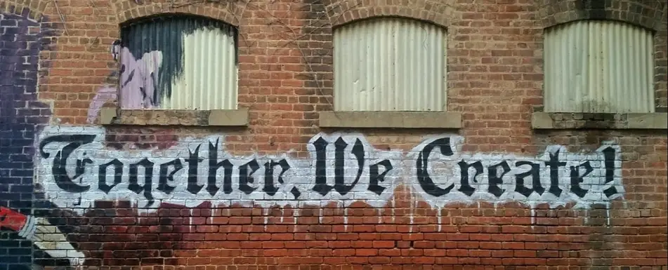 A graffiti art on a wall that says 'Together We Create!'.