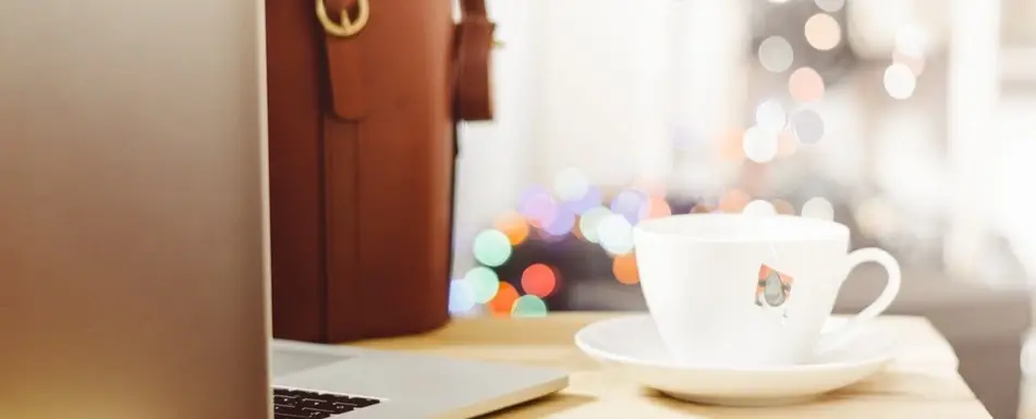 A teacup next to a laptop.