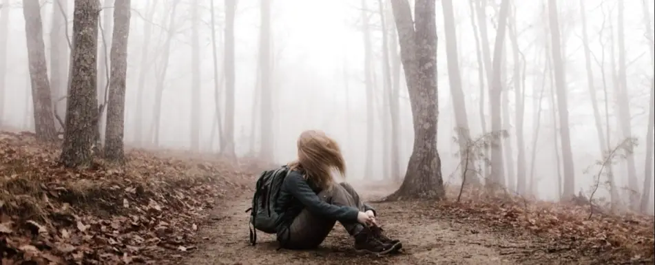 A person sitting down in the middle of a forest.