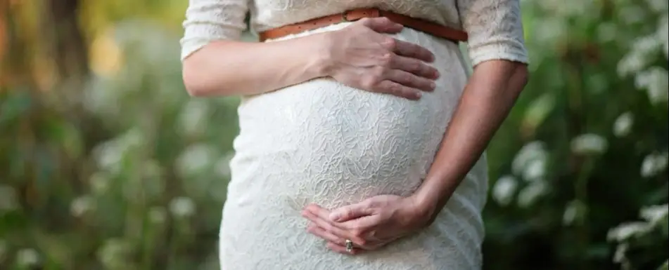 A pregnant woman holds her belly.