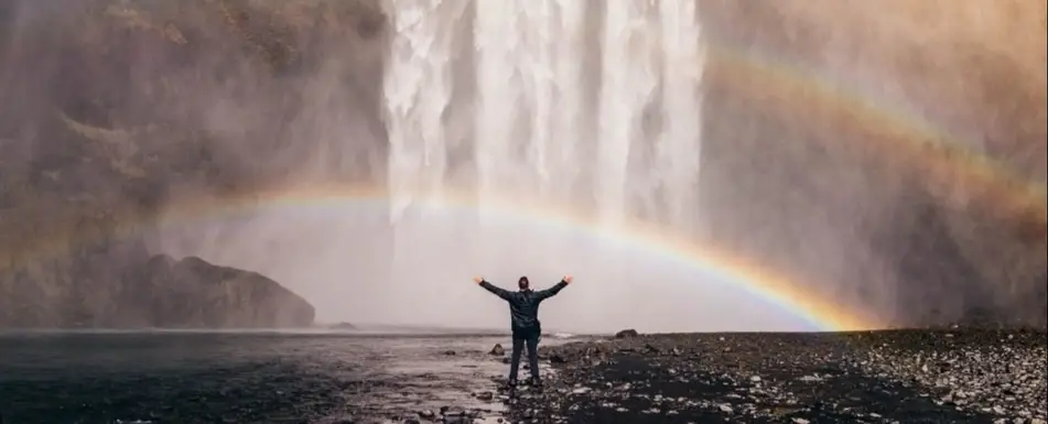A person standing underneath a rainbow.