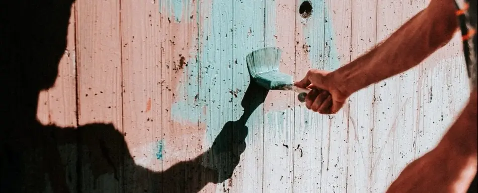 A man paints a fence blue.