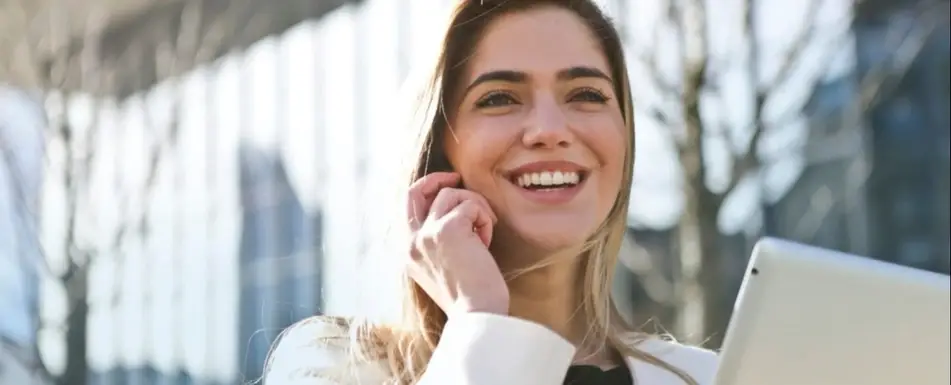 A blond woman smiling while on the phone.