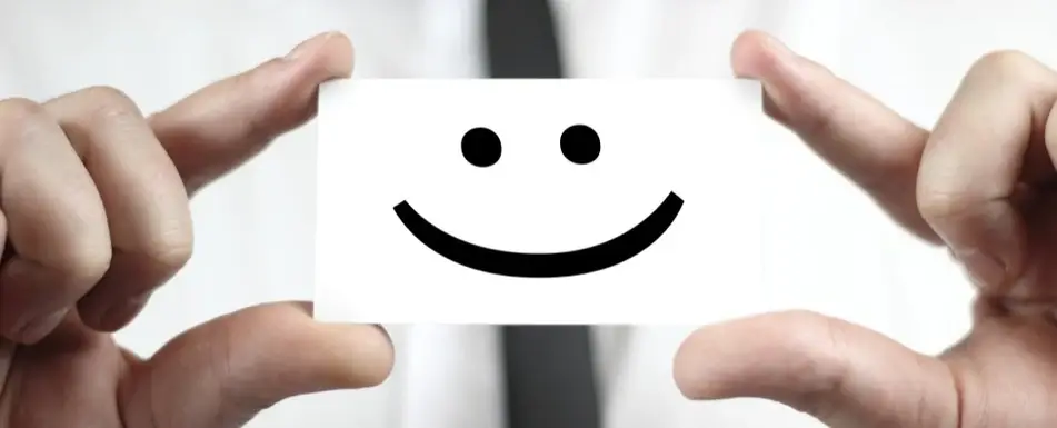 A man holds up a card with a smiley face on it.