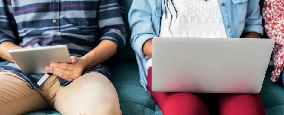 Someone using an tablet and someone else using a laptop.