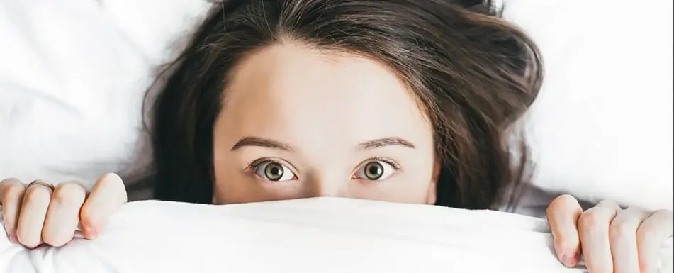 Someone peeking out of a bed sheet.