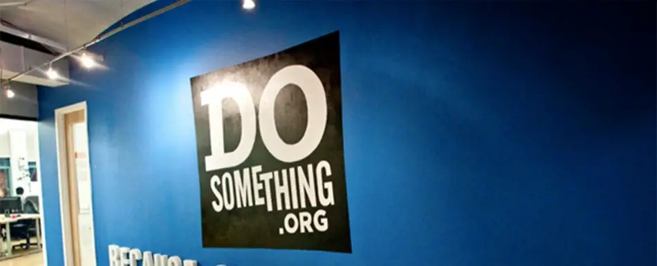 A poster of 'Do Something.Org' on a blue wall.