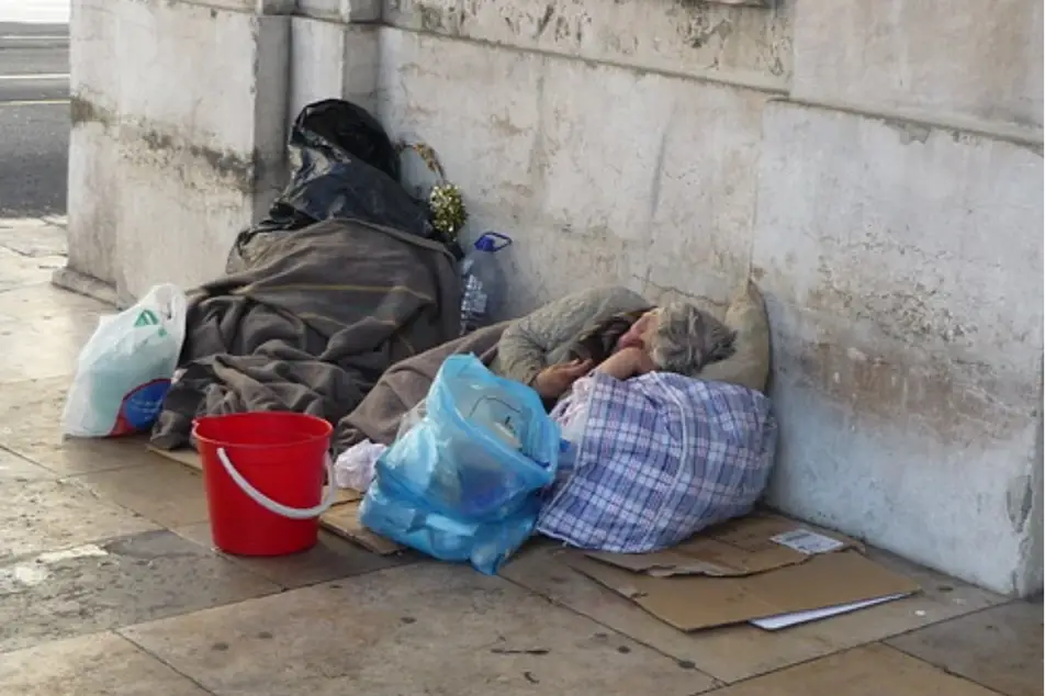 Una persona en situación de calle durmiendo en una acera