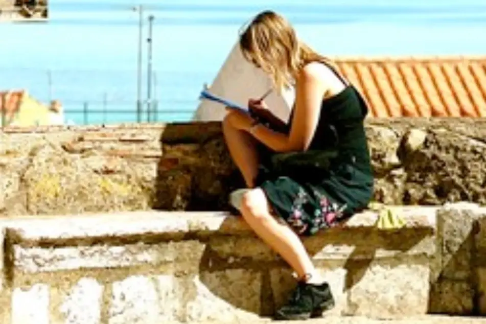 Una chica en una acera escribiendo en un cuaderno
