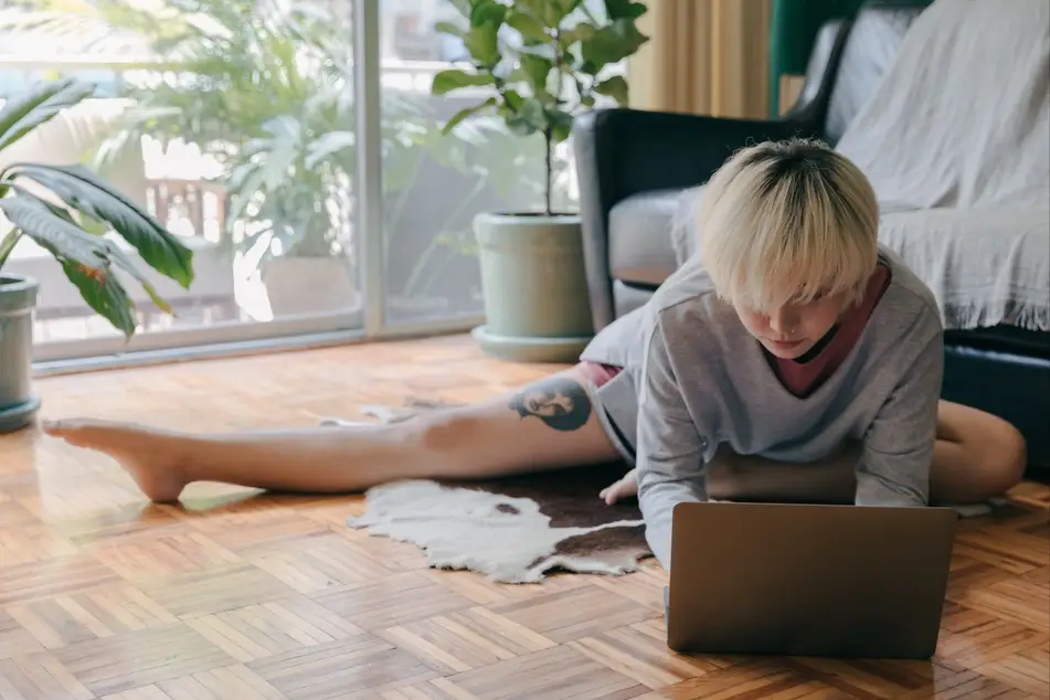 woman stretching on floor in front of laptop