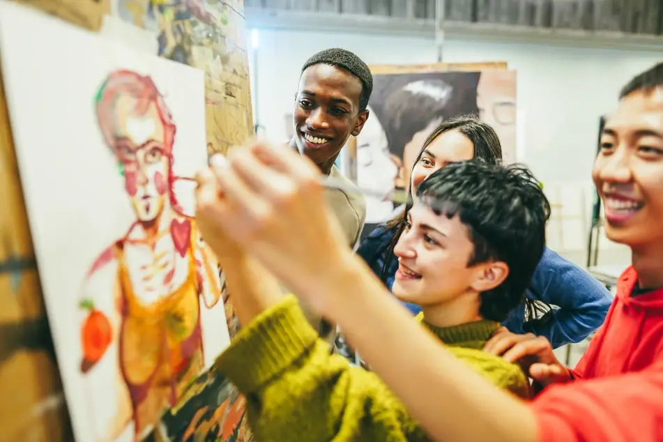 Four smiling people working together on a painting.