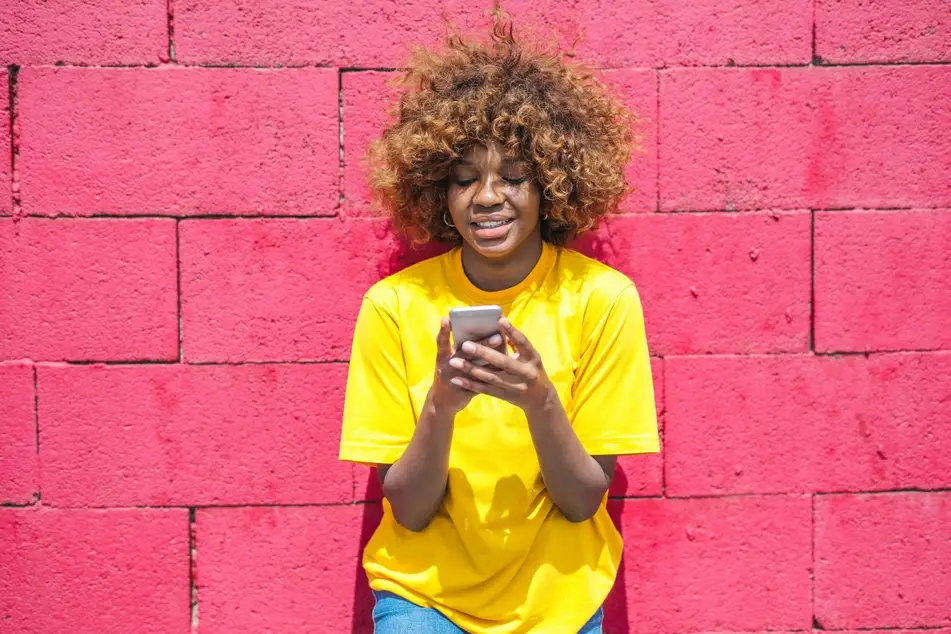 woman in yellow shirt smiling looking at phone