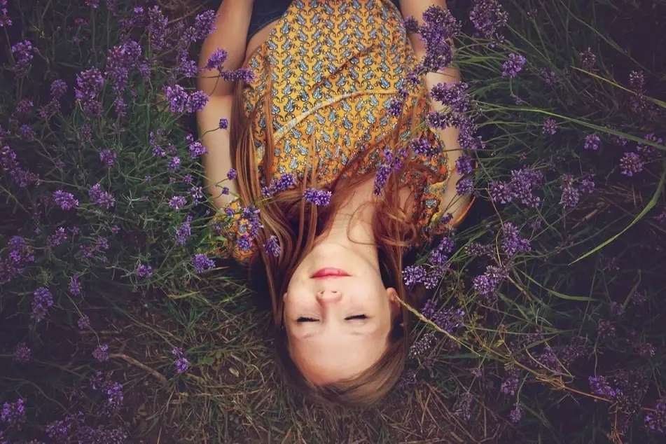 A woman rests in a field of purple flowers.