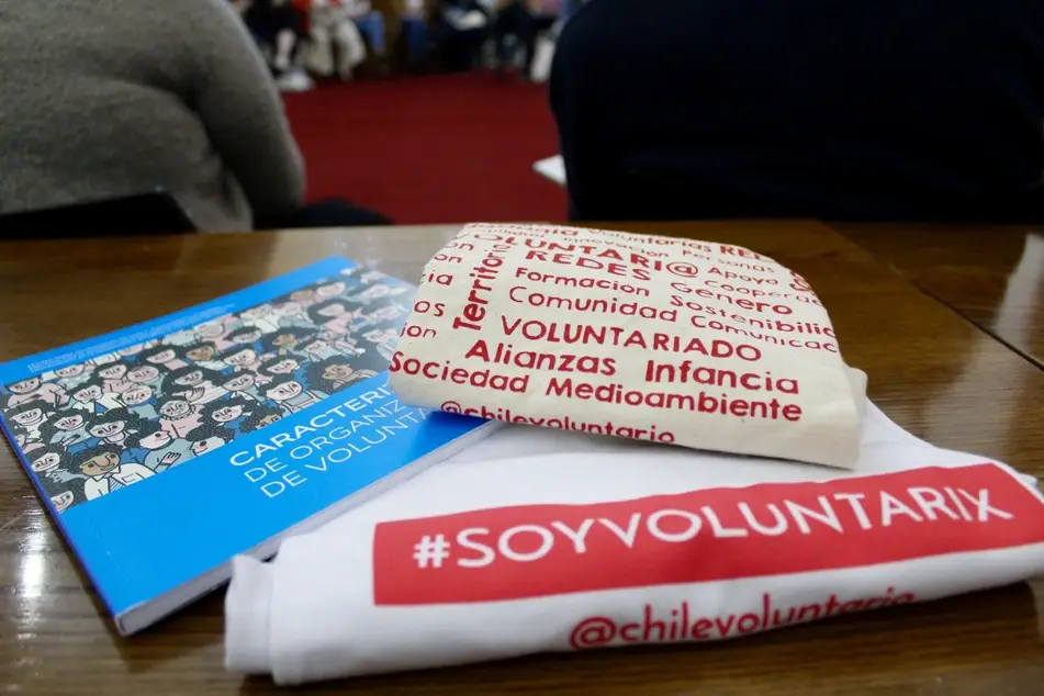 Libro y camiesta con logo de la Red Nacional de Voluntariado en Chile