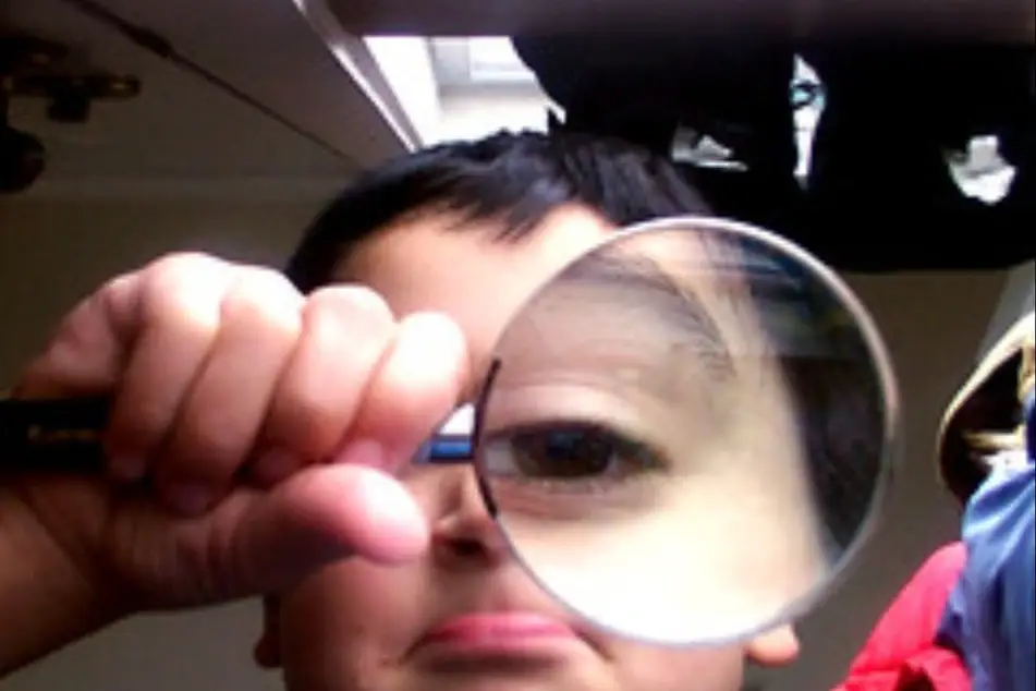 Un niño mirando algo a través de una lupa