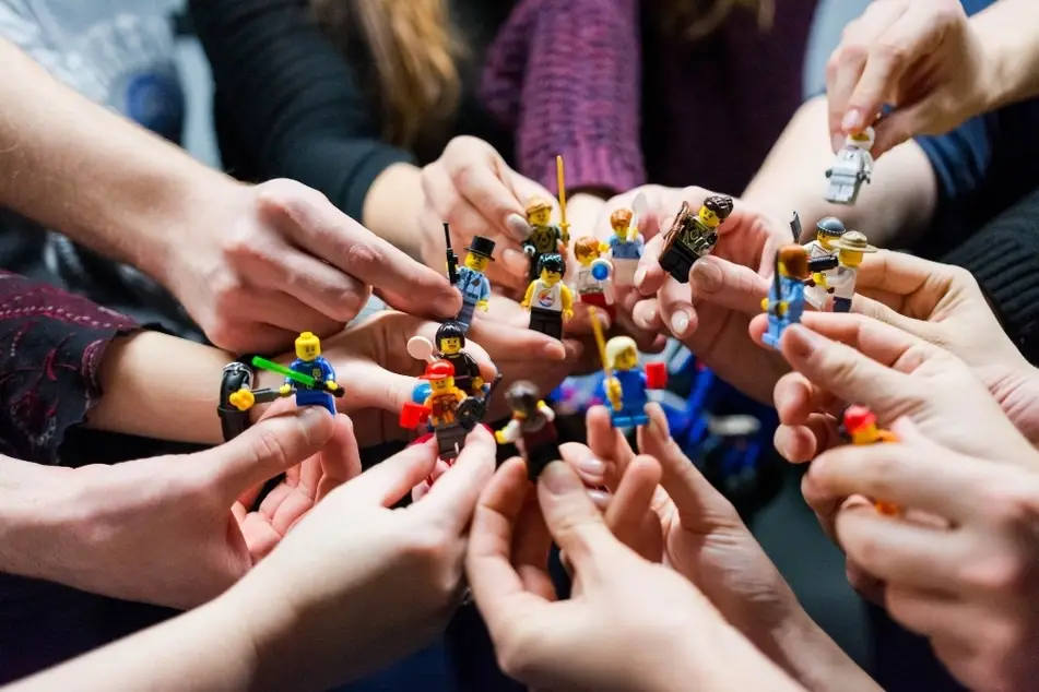 Equipo de personas reunidas con muñecos legos en sus manos