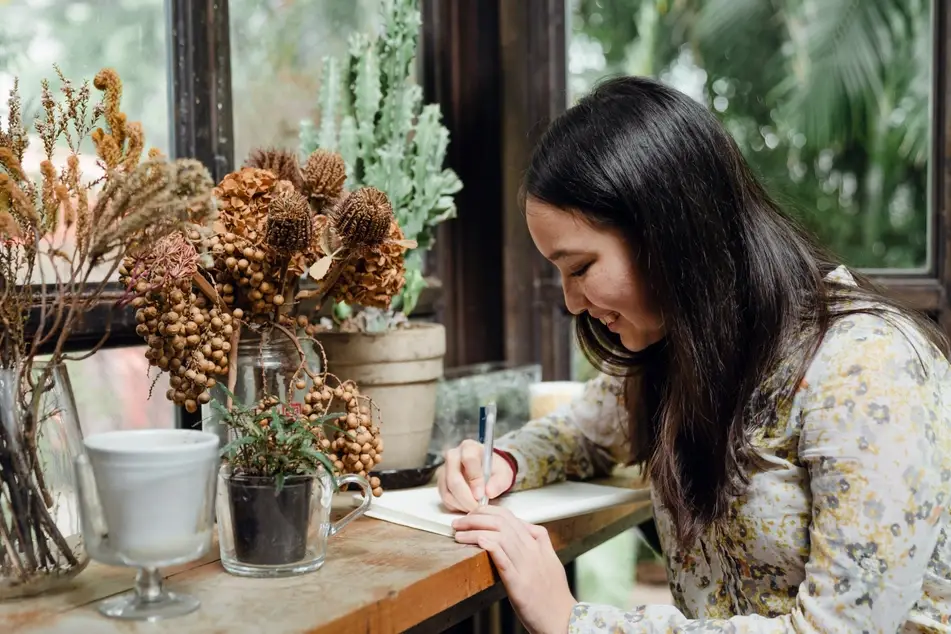 woman writing surrounded by plants