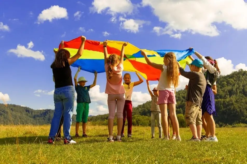 Varias niñas jugando levantando una tela de colores