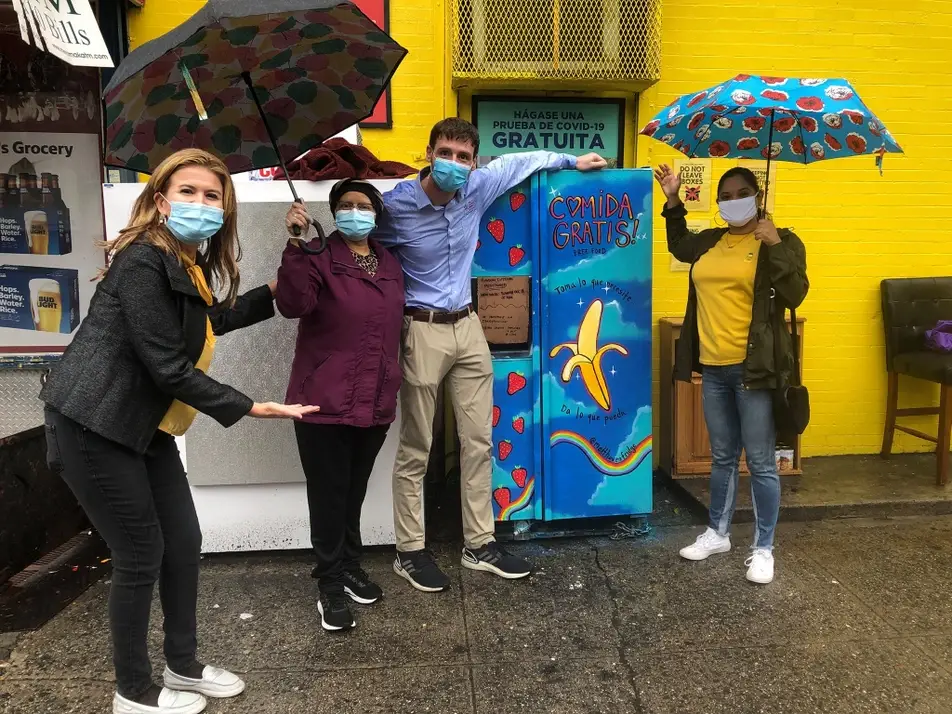 people standing next to a community fridge